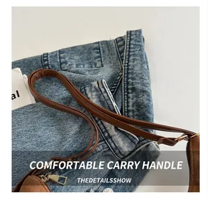 Détail des poignées en cuir marron confortables et du zip métallique sur le grand sac
