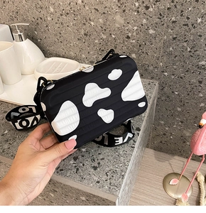 Detail of mini suitcase crossbody bag featuring cow print and LOVE letter wide strap