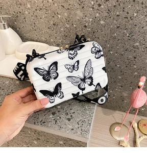 Macro detail of mini hardshell suitcase bag with butterfly print and lettered strap