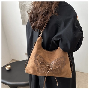 Détail du sac hobo en daim marron avec grande applique papillon en cuir et nœud à lacets