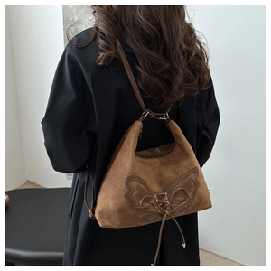 Détail d'un sac à bandoulière en daim marron foncé avec coutures papillon et lacets croisés