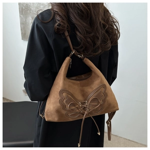 Détail du sac à épaule en daim marron avec un grand nœud et un design de laçage
