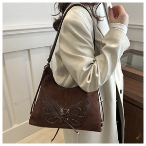 Vue détaillée du sac à bandoulière en daim marron avec applique papillon en cuir unique
