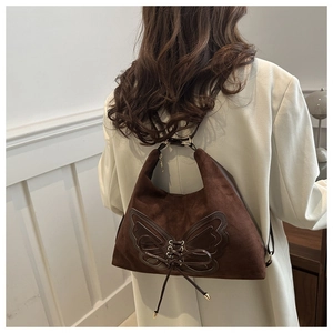 Détail du sac bandoulière en daim marron foncé avec nœud en cuir et laçage à l'arrière