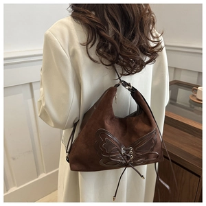 Détail d'un grand sac cabas en daim marron avec nœud en cuir et rubans décoratifs