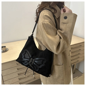 Détail d'un sac à épaule rétro en daim noir avec nœud en cuir et finitions de laçage