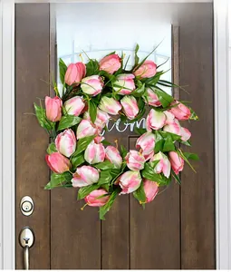 Close-up of pink and white tulip wreath with green leaves on dark wooden door