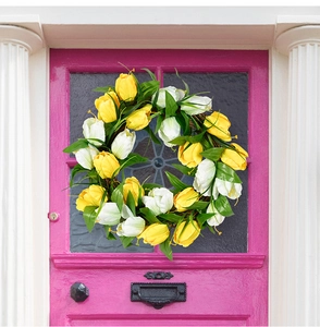 Detail of yellow and white faux tulips wreath hanging on a vibrant pink door