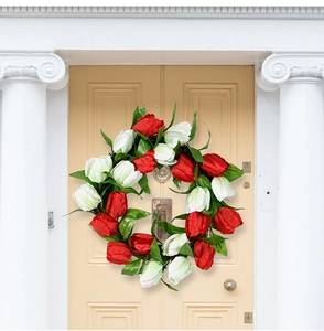 Close-up of red and white artificial tulip wreath hanging on a light yellow wooden door