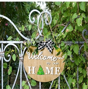 Detail of wooden welcome sign with 3D letters and seasonal tree icon on white fence