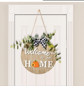 Detailed view of wooden home door sign with eucalyptus leaves and a checkered bow