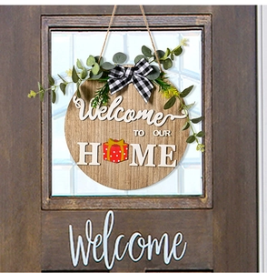 Detail of wooden welcome sign with eucalyptus leaves and bow on a dark brown door