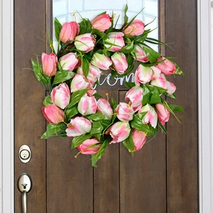 Pink tulip wreath with green leaves for home wall decor on a brown wooden door