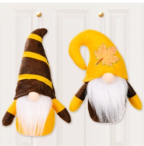 Close-up of autumn gnome plush ornaments with maple leaf details on a white door