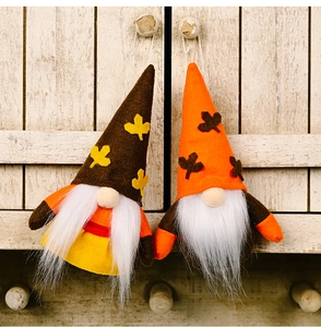 Detail of plush fall gnomes with maple leaves hanging on a vintage wooden cabinet