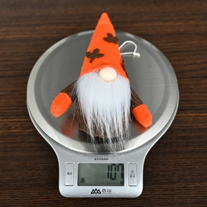 Detail shot of a plush gnome autumn ornament being weighed on a digital scale for accuracy