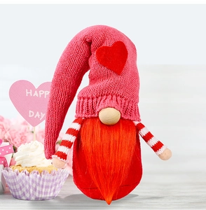 Detail of a Valentine gnome with pink knitted hat and red felt heart on wood background