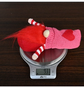 Detailed view of handmade knitted heart gnome being weighed on a digital scale at 93.1g