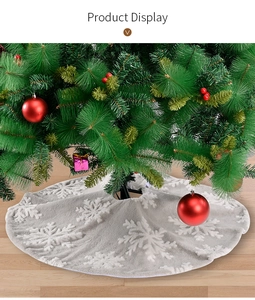 Detail of grey plush Christmas tree skirt with white 3D snowflakes on wood floor