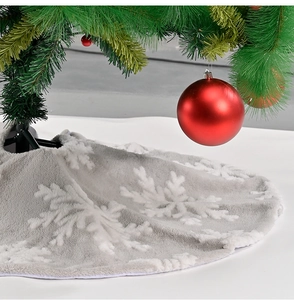 Detail of plush grey Christmas tree skirt featuring white snowflake patterns and soft texture