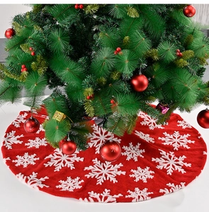 Close-up of plush red Christmas tree skirt with white snowflake patterns for holiday decor