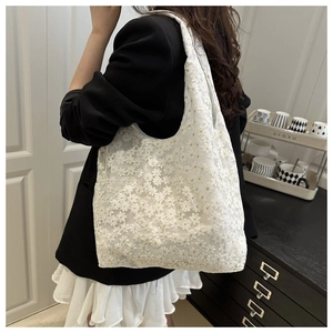 Detail showing white lace crochet tote bag with daisy floral embroidery patterns