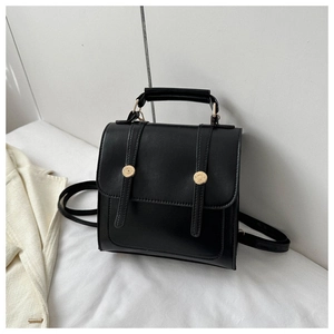 Détail d'un mini sac à dos en similicuir noir avec boucles dorées sur fond décoratif