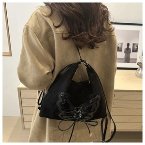 Détail du sac hobo en daim noir avec grand papillon en cuir et laçage style corset chic