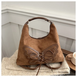 Détail du sac cabas en daim marron avec patch papillon décoratif en cuir et laçage élégant
