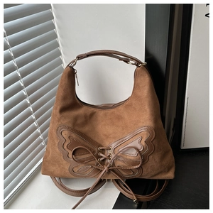Détail de l'applique papillon géante en cuir marron et laçage décoratif sur le sac