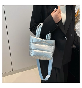 Détail du sac seau matelassé argenté avec bandoulière bleu clair porté par un mannequin