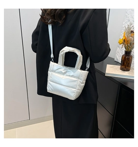 Sac seau matelassé blanc perle porté en bandoulière sur un mannequin élégant