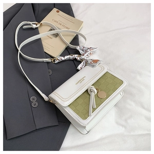 Detail of green plaid crossbody bag with silk scarf accent and gold charm on suit jacket