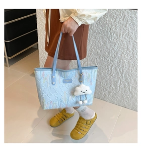 Light blue quilted tote bag detail with colorful embroidery and white cloud plush charm