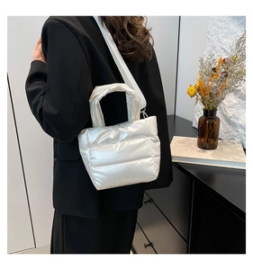 Détail d'un sac seau matelassé blanc perle avec bandoulière tissée et crochets en métal