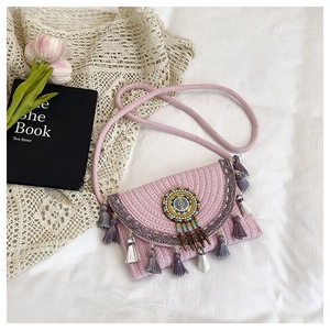 Dettaglio borsa a tracolla in paglia rosa con nappe colorate e decorazione etnica