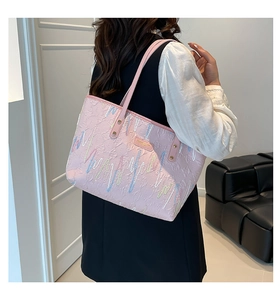 Detail of pink embroidered tote bag with colorful wave stitching and metal logo plate