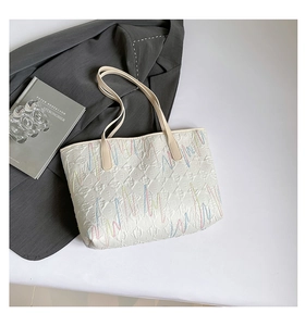 Macro detail of quilted tote bag with wave embroidery and subtle monogram texture