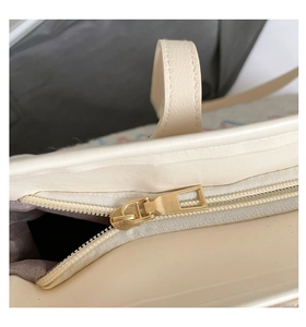 Close-up of golden metal zipper and beige synthetic leather stitching on tote bag