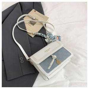 Detail of woven texture flap on blue and white crossbody bag with decorative silk scarf