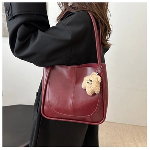 Detail of burgundy leather tote featuring U-shaped stitching and plush star charm