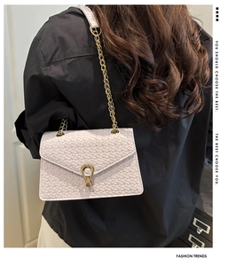 Détail du sac à bandoulière beige clair avec chaîne dorée et fermoir métallique unique