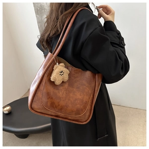 Brown vintage faux leather tote bag with plush bear charm and long shoulder straps