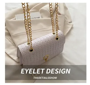 Détail de la texture tissée et des œillets de chaîne dorés sur le rabat du sac