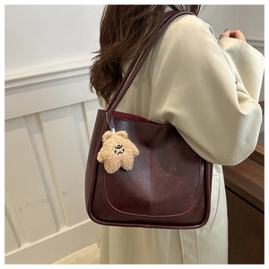 Detail of dark burgundy retro tote bag with star plush charm on a model's shoulder