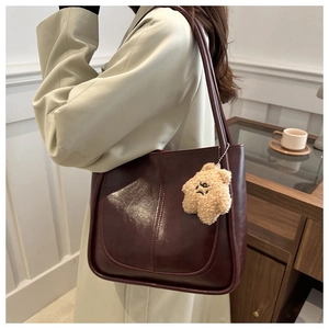 Detail of wine red faux leather tote bag with glossy finish and plush star charm
