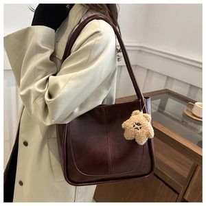 Detail of dark burgundy tote bag featuring vertical stitching and a cute plush star charm