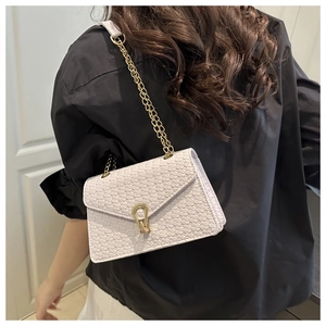 Detail of lavender woven square bag featuring a gold horseshoe clasp and chain strap