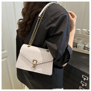 Close-up of white crossbody bag with woven texture and gold U-shaped metal buckle