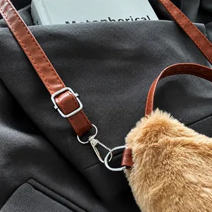 Detalle de la correa ajustable de cuero y hebilla metálica en el bolso de felpa